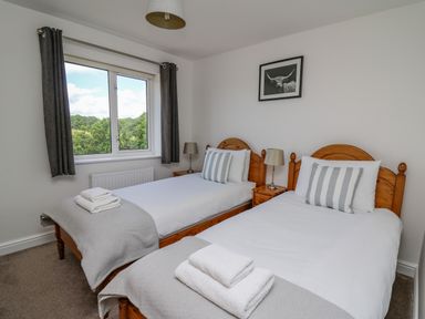 A bedroom with two single beds pillows and towels near a window at Foxes Meadow in Howey near Llandrindod Wells
