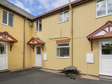 The exterior of connected houses with beige walls white doors and windows and small roofs above doors at Pheasant Wood in Howey near Llandrindod Wells