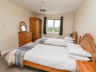 A bedroom with two single beds with wooden headboards and blue plaid blankets at Pheasant Wood in Howey near Llandrindod Wells