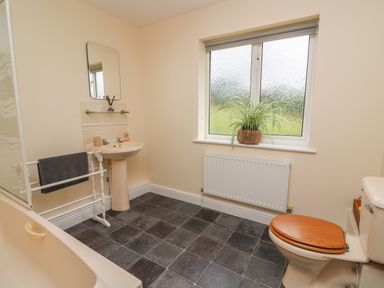 A bathroom with a bathtub sink toilet towel rack and a window with a plant on the sill at Pheasant Wood in Howey near Llandrindod Wells