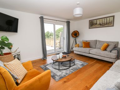 A living room with grey sofas and orange cushions a yellow armchair wooden floor and a coffee table at Pheasant Wood in Howey near Llandrindod Wells
