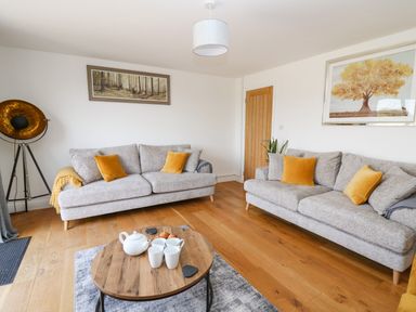 A living room with two grey sofas and orange cushions at Pheasant Wood in Howey near Llandrindod Wells