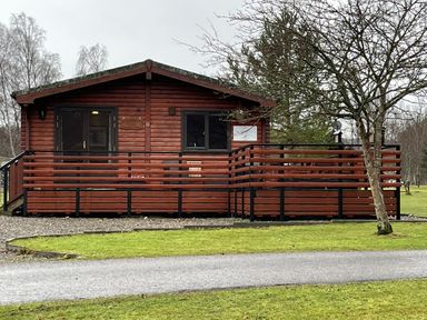 A cabin with a deck and sliding door at Wildcat Lodge in Newtonmore