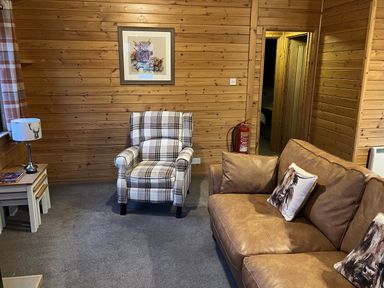 A living room with an armchair and a sofa at Wildcat Lodge in Newtonmore