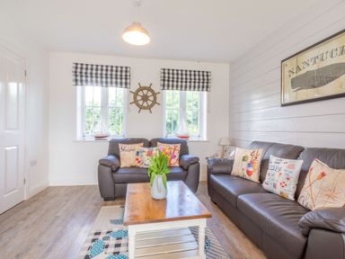 A living room with two leather sofas and a wooden coffee table with flowers at Lilipad Cottage The Bay near Filey