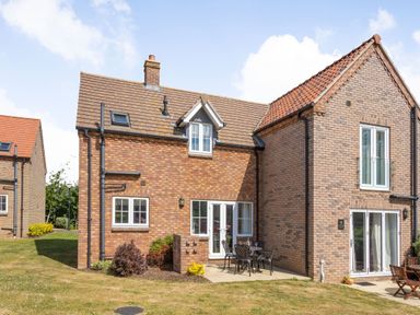 A brick house with outdoor patio furniture and grass lawn at Lilipad Cottage The Bay near Filey