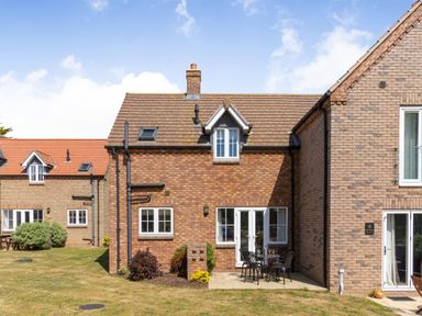 The exterior of a brick house with a small patio and outdoor table and chairs at Lilipad Cottage The Bay near Filey