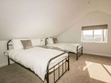 A bedroom with two single beds a nightstand and a window at The Beach Halt in Perranporth