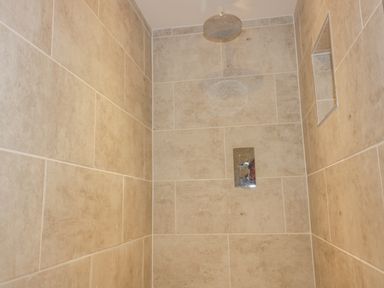 A tiled shower area with a rain shower head and a recessed shelf at The Beach Halt in Perranporth