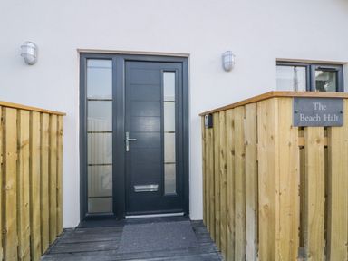 A front door with glass panels and wooden railing with a sign saying The Beach Halt in Perranporth