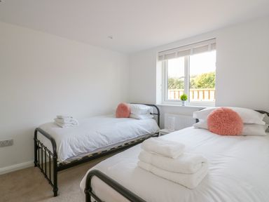 A bedroom with two single beds white linens and folded towels on the beds at The Beach Halt in Perranporth