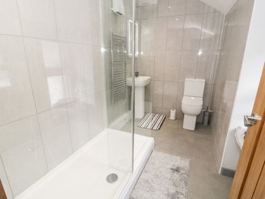 A bathroom with a walk-in shower, toilet, sink, and towel hanging at Bryn Alun in Tanygrisiau near Blaenau Ffestiniog
