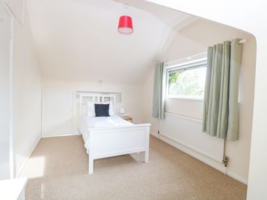 A bedroom with a white single bed a window with curtains and a bedside table at Swan Dyke Cottage in Horning near Wroxham
