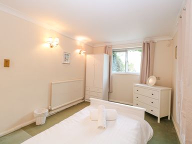 A bedroom with a bed with towels on it a white wardrobe a white dresser and a window at Swan Dyke Cottage in Horning near Wroxham