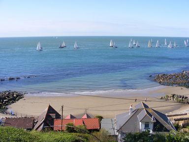 A beach with houses in front and many sailboats on the water at Chale Farm Lodge in Chale