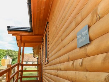 A wooden porch with railing and a sign that reads Chale Farm Lodge at Chale Farm Lodge in Chale