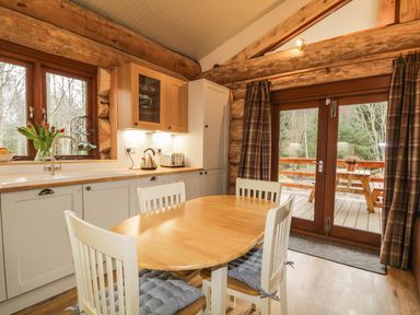 A kitchen with wooden table and four chairs a sink and cabinets a glass door leads to an outdoor area at Heron Lodge in North Kessock