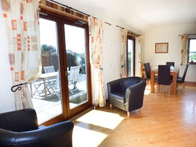 A dining area with table and chairs and black armchairs near glass doors with patterned curtains at The Old Granary in Spittal