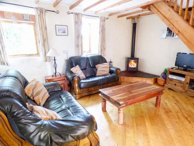 A living room with wooden floors two leather sofas a wooden coffee table a fireplace and a TV at The Old Granary in Spittal