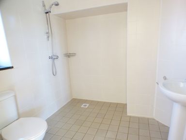 A bathroom with a shower area a toilet and a pedestal sink at The Old Granary in Spittal