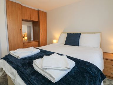 A bedroom with a bed made with white linens and a dark blue throw at The Cottage in Chilsworthy near Holsworthy