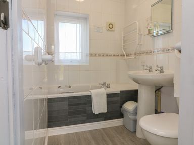 A bathroom with a bathtub a white towel a sink a mirror and a toilet at The Cottage in Chilsworthy near Holsworthy