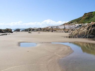 A sandy beach with rocks and pools of water near the shoreline at Ancarva Near Kingsands