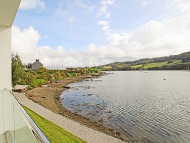 A view of a shoreline with small boats on water and grassy hills at Ancarva Near Kingsands