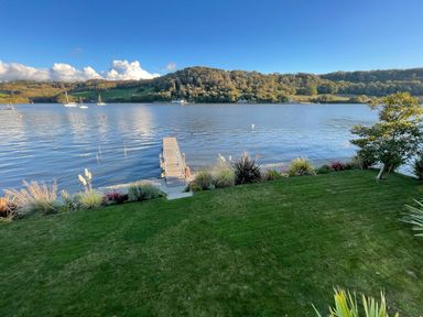A waterfront garden with a dock extending into a river and boats on the water at Ancarva Near Kingsands