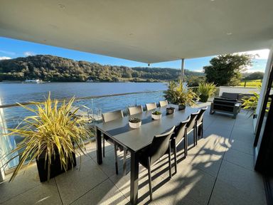 An outdoor dining area with a table and chairs overlooking a body of water at Ancarva Near Kingsands