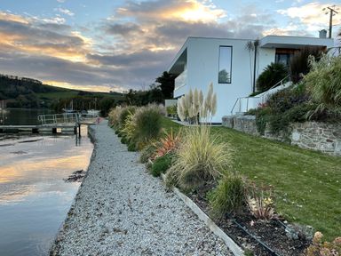 A modern house with a waterfront view and a gravel path beside a garden at Ancarva Near Kingsands