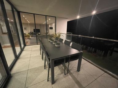 An outdoor balcony with a black dining table and chairs and plants on the table near glass doors at Ancarva Near Kingsands