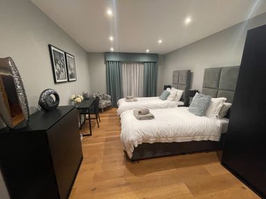 A bedroom with two twin beds with gray headboards and white bedding at Ancarva Near Kingsands