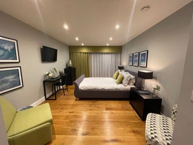 A bedroom with a bed a television a desk chairs and framed pictures on the walls at Ancarva Near Kingsands