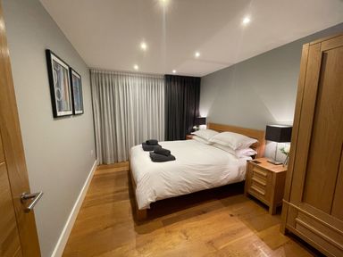 A bedroom with a wooden bed and side tables with lamps and folded towels on bed at Ancarva Near Kingsands