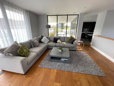 A living room with a gray sectional sofa, a gray area rug, a gray coffee table with a plant, and a floor lamp at Ancarva Near Kingsands