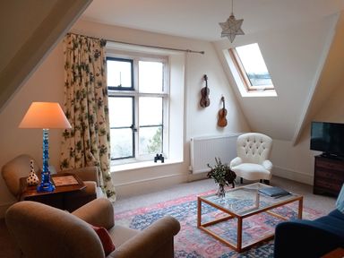 A sitting room with armchairs a glass coffee table a carpet and violins on the wall at Haslington House in Malvern