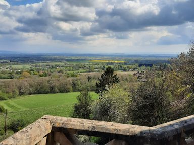A rural landscape with fields trees and cloudy sky viewed from behind a stone wall at Haslington House in Malvern