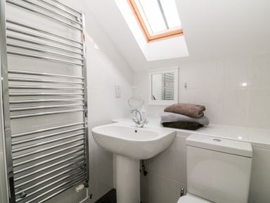 A bathroom with a sink toilet folded towels mirror and a heated towel rail at Honeysuckle Cottage in Ashwater near Holsworthy