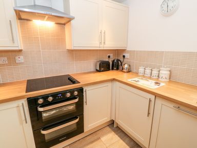 A kitchen with a black electric oven and stove a wooden countertop a toaster kettle canisters and a wall clock at The Hayloft in Milton near Brampton