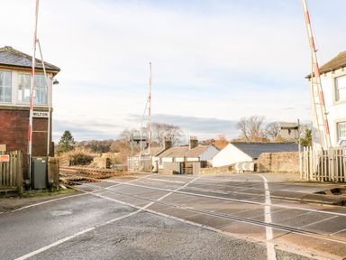 A railway crossing with barriers and rail tracks near buildings at Milton near Brampton