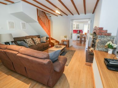A living room with two brown sofas a wooden coffee table wooden floors stairs and a stone fireplace at Tryfan in Llanberis