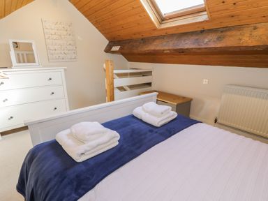 A bedroom with a bed with folded towels a chest of drawers a skylight window and wooden ceiling at Tryfan in Llanberis