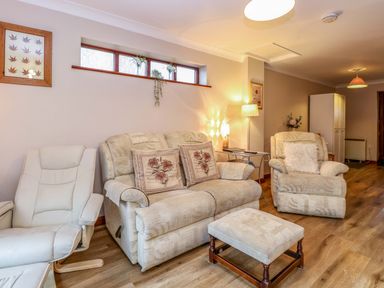A living room with sofas armchair ottoman and lamps at Kingfisher in Wattisfield near Rickinghall and Diss