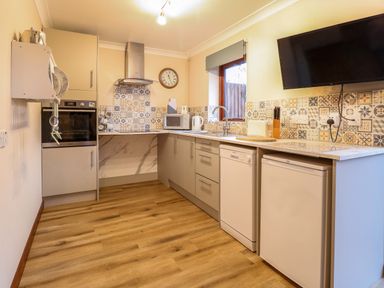 A kitchen with oven microwave dishwasher fridge sink and wall mounted television at Kingfisher in Wattisfield near Rickinghall and Diss