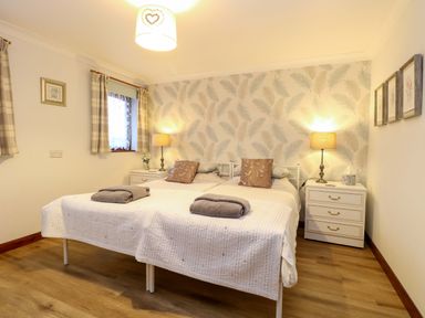 A bedroom with two single beds side by side bedside tables with lamps and windows with plaid curtains at Kingfisher Wattisfield near Rickinghall and Diss