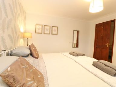 A bedroom with a bed with pillows and towels on it a lamp on a side table and pictures on the wall at Kingfisher Wattisfield near Rickinghall and Diss