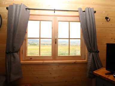 A wooden window with curtains tied back showing a rural landscape at The Shooting Lodge in Longnor