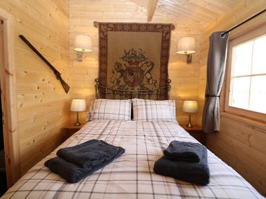 A bedroom with a double bed with folded towels on it two bedside tables with lamps and a window with curtains at The Shooting Lodge in Longnor