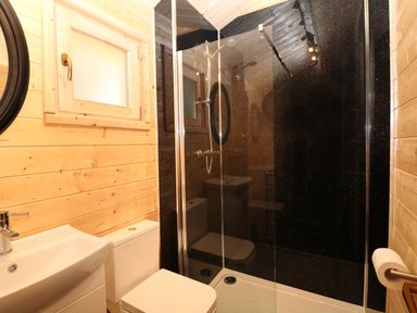 A bathroom with a sink toilet and a shower with black tiled walls at The Shooting Lodge in Longnor